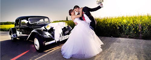 Esküvői pár egy mező elött egy olds mobil autóval Bonnie és Clyde stílusban